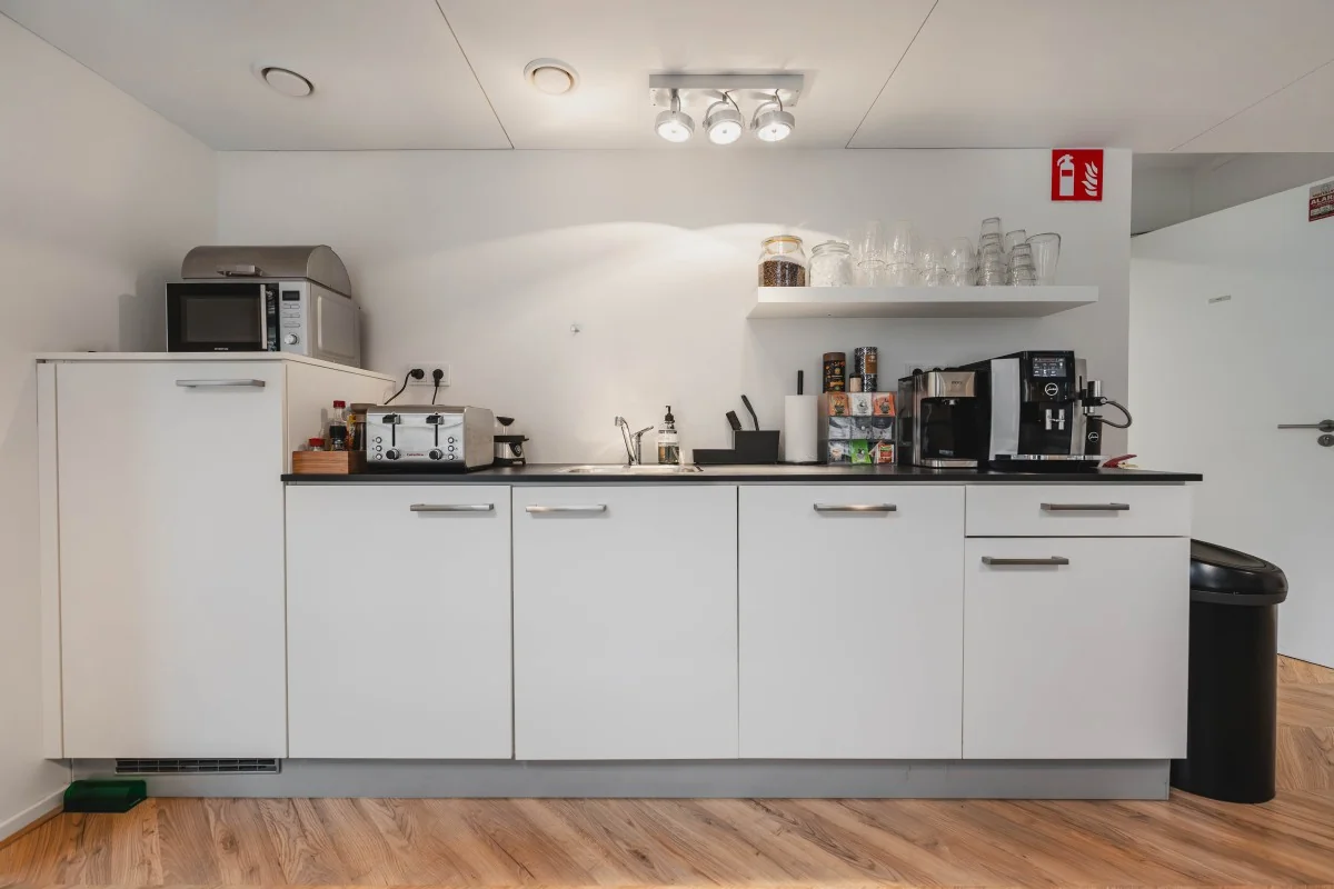 Kleine moderne pantrykeuken in een kantoor aan de Korte Reguliersdwarsstraat met koffiezetapparaat, magnetron en spoelbak.